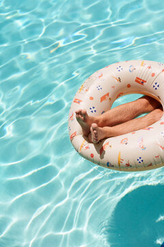 Man's legs relax in pool inner tube