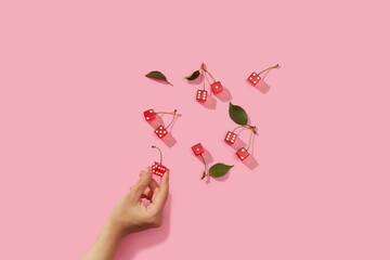 Hand of unknown human taking red gaming dice out of pink surface