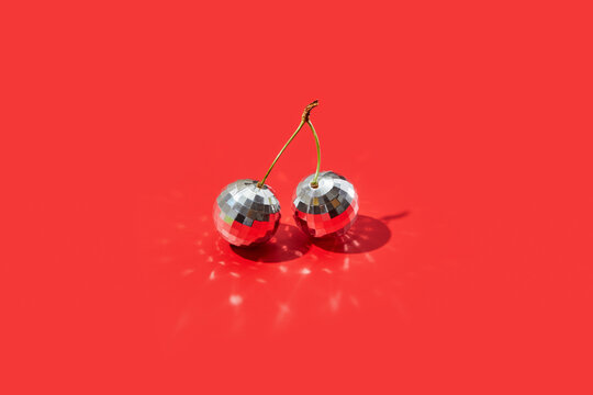 Pair of disco balls placed on floor in red studio creating sunbeams