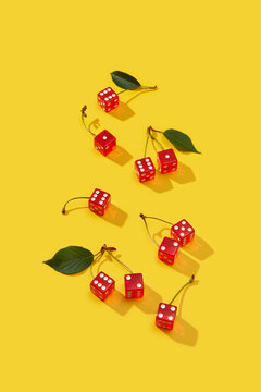 Ruby cubes attached to cherry stems with leaves on yellow background