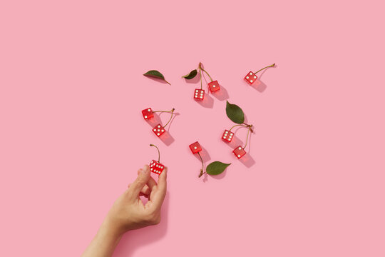 Hand of unknown human taking red gaming dice out of pink surface