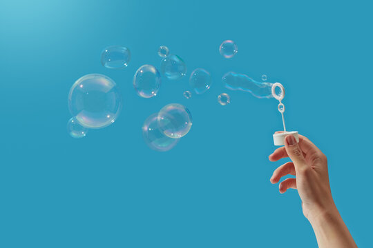 Person with white wand creating set of soap bubbles