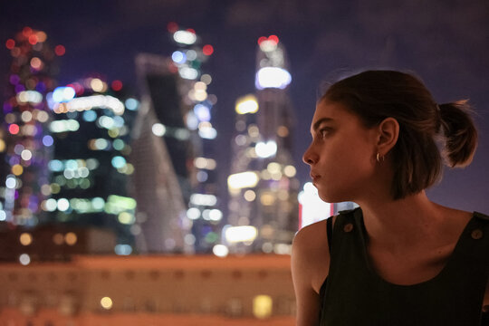 Young woman contemplating the glow of city lights at night