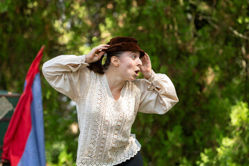 Actress adjusting hat and looking off camera during open air theater performance