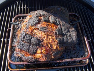 Pork shoulder smoked on a charcoal grill for pulled pork