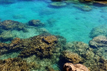 Romantic rocky shoreline with stones, clear calm paradise sea. Turquoise ocean, vacation destination. Paradise bay with clear water, travel photography.