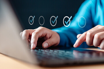 mark, choose, checklist, check, checkmark, password, checkbox, survey, complete, tick. A person is typing on a laptop with a check mark on the screen, using a keyboard and the laptop is on a table.