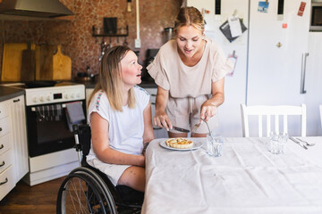 Woman with a Disability Enjoying Lunch with Assistant in Kitchen