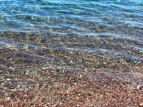Sea clear calm water on pebbly beach.