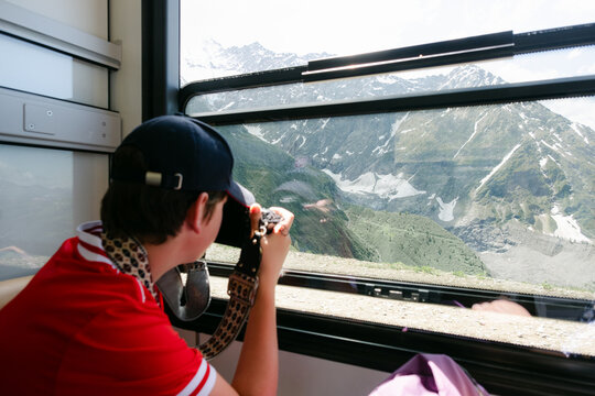 teen taking photo of the landscape in the Tram in the French Alps