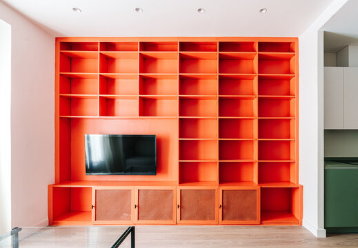 A modern living room with an orange built-in wall unit