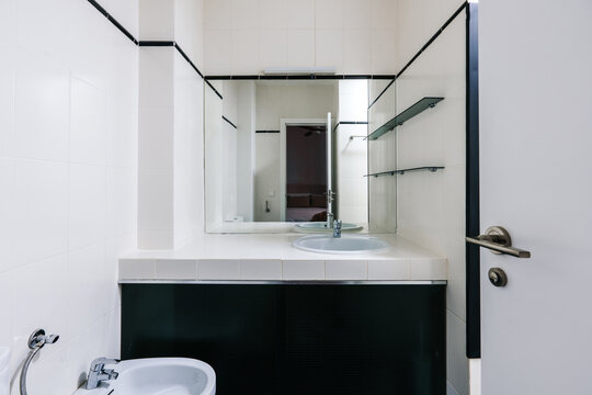 A small, modern bathroom with white tiled walls