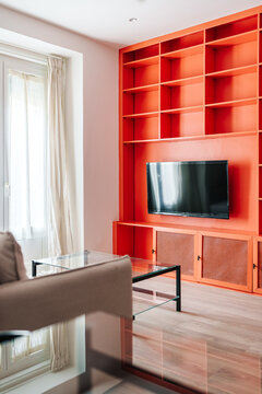 A modern living room with a large built-in orange shelving unit