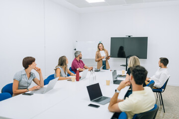 Businesspeople sitting around table with laptops in conference hall