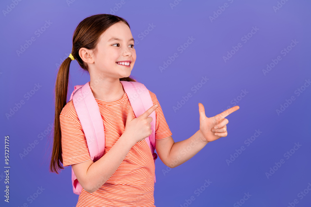 Wall mural Photo portrait of lovely small girl backpack point look empty space dressed stylish red garment isolated on violet color background