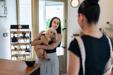 Woman holding her dog and talking to a pet shop worker