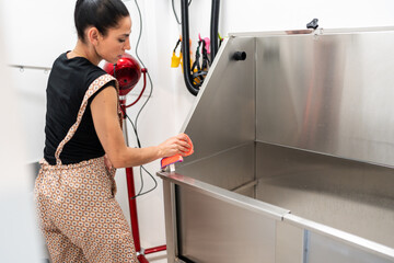 Dog groomer cleaning dog bathtub in salon