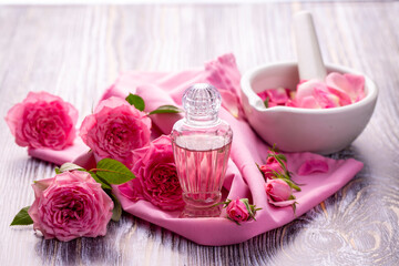 Bottles of essential rose oil and flowers
