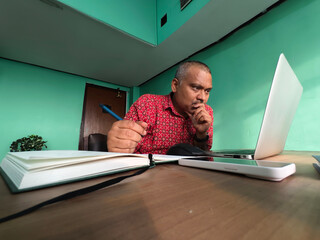 Middle aged Indian man doing office work in laptop