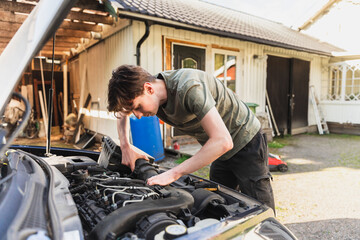 Young Mechanic Fixing Car Outside Home