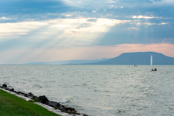 Obraz premium sailing on lake Balaton with Badacsony hill in the background and beautiful light rays