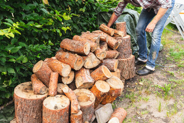 Man Standing by Stored Wood Ready for Chopping