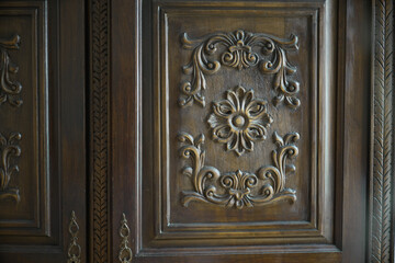 Close-up of detailed floral carvings on an antique wooden wardrobe, highlighting intricate craftsmanship and vintage design in home furniture, suitable for classic interior decor
