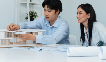 Portrait of cooperative engineer team working together to measure house model by using ruler and...