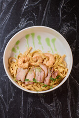 Enjoy a bowl of tasty pasta with shrimp and crispy bacon, garnished with fresh herbs