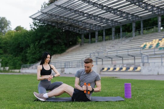 Fitness man making crunches with dumbbells during couples training