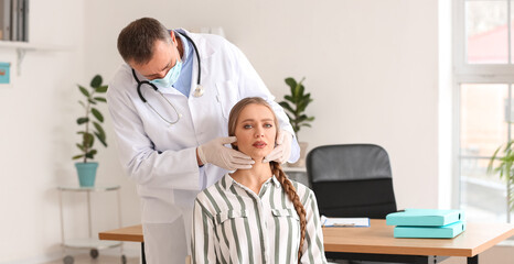 Fototapeta premium Doctor examining woman's neck in clinic