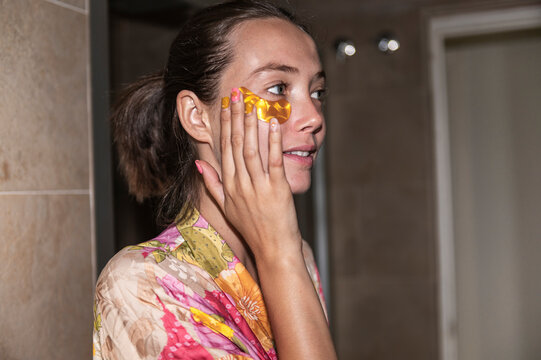 Woman applying under-eye patches, lo-fi, direct flash