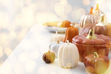 Candles in shape of pumpkins, tableware and decorations on light background