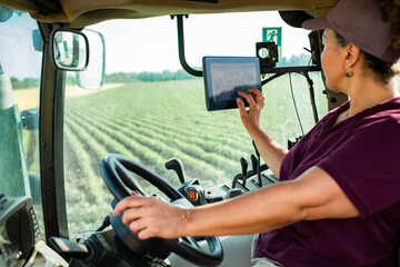 Middle aged female farmer driving tractor on field