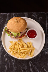 A Delicious Burger served with Crispy Fries and a side of Ketchup on a Dark Marble Table