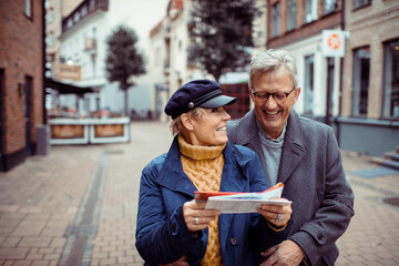 Senior couple laughing and exploring city with a map