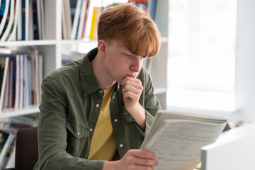 Student engaged in reading his notebook at library