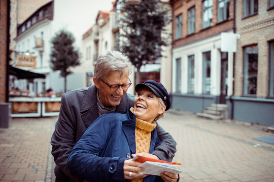 Senior couple laughing and exploring city with a map