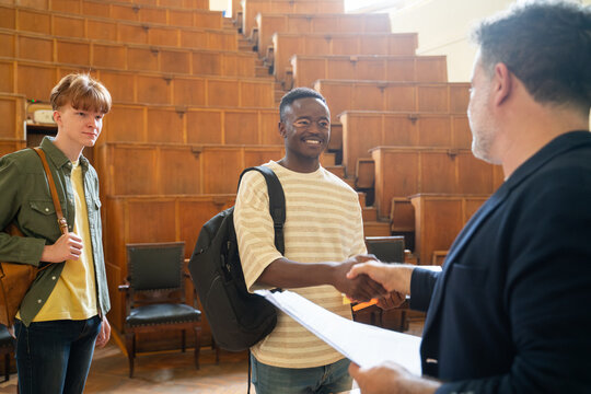Student handshake with professor in lecture hall 