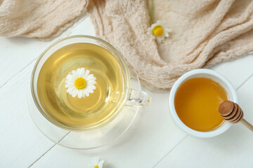 Cup of hot chamomile tea with honey on white wooden background
