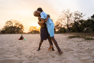 Two african kids wrestling on sand during golden hour in senegal