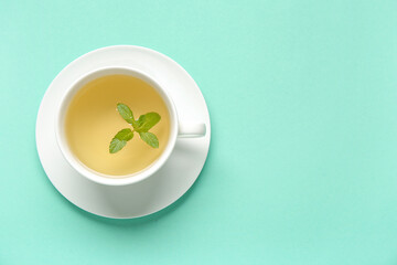 Cup of fresh mint tea on turquoise background