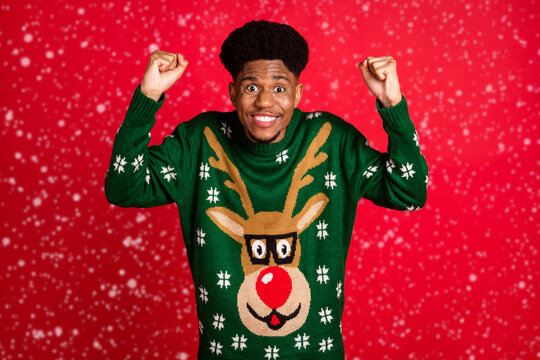 Portrait of attractive lucky cheerful guy wearing ugly jumper having fun rejoicing isolated over bright red color background