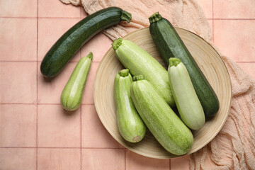Plate with fresh zucchini on beige tile background