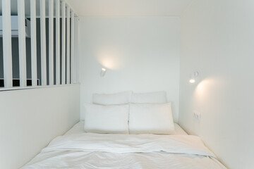A cozy bed in a small room, adorned with white sheets and pillows