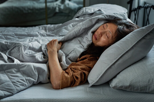 Senior Asian Woman Sleeping Under Blankers 