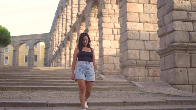 Aqueduct of Segovia visited by girl travelling to Spain walking arround this artichetectural structure which is considered as a world heritage.