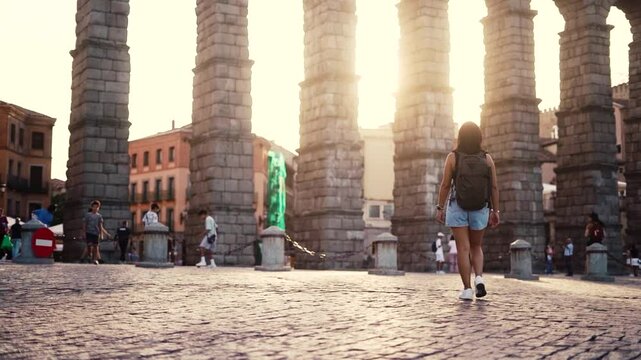 Aqueduct of Segovia visited by girl travelling to Spain walking arround this artichetectural structure which is considered as a world heritage.