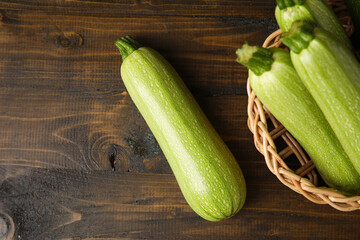 Wicker bowl with fresh green zucchini on wooden background