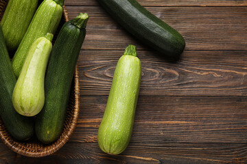 Wicker bowl with fresh green zucchini on wooden background